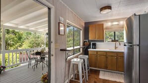 Une cuisine avec des meubles en bois, un réfrigérateur en acier inoxydable et un tabouret de bar.