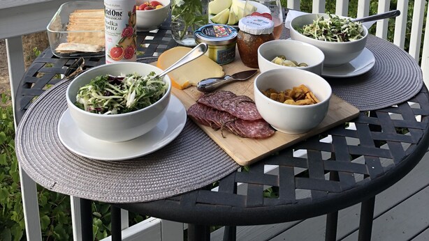 Une table dressée avec de la nourriture et des boissons sur un balcon donnant sur un vignoble.