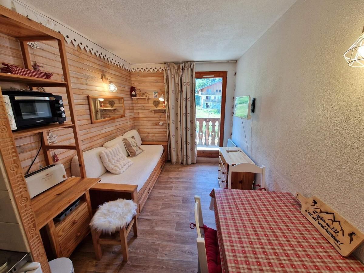 A cozy room with a wooden interior, a sofa, a small table, a microwave, and a view of the outside.