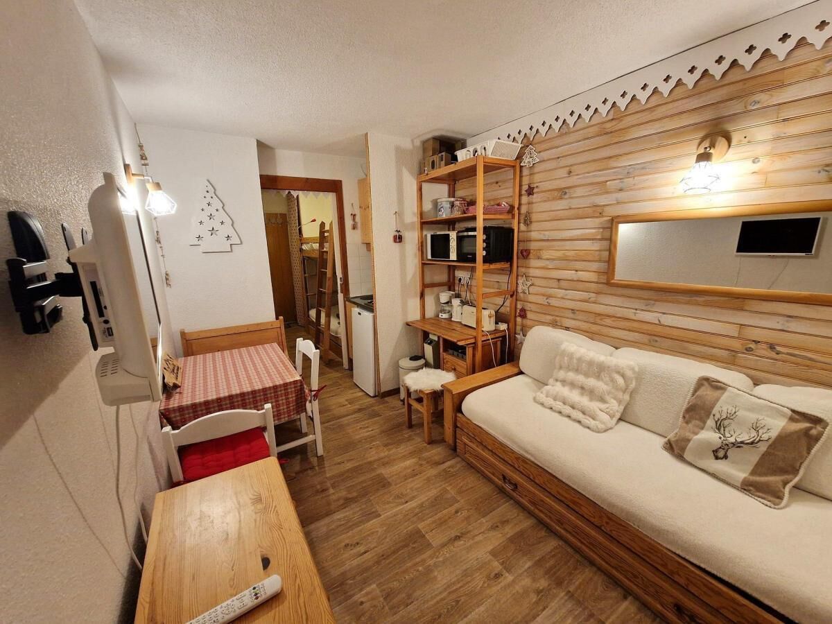 A cozy room with a wooden sofa, a small table, a chair, a wooden shelf, and a mirror on the wall.