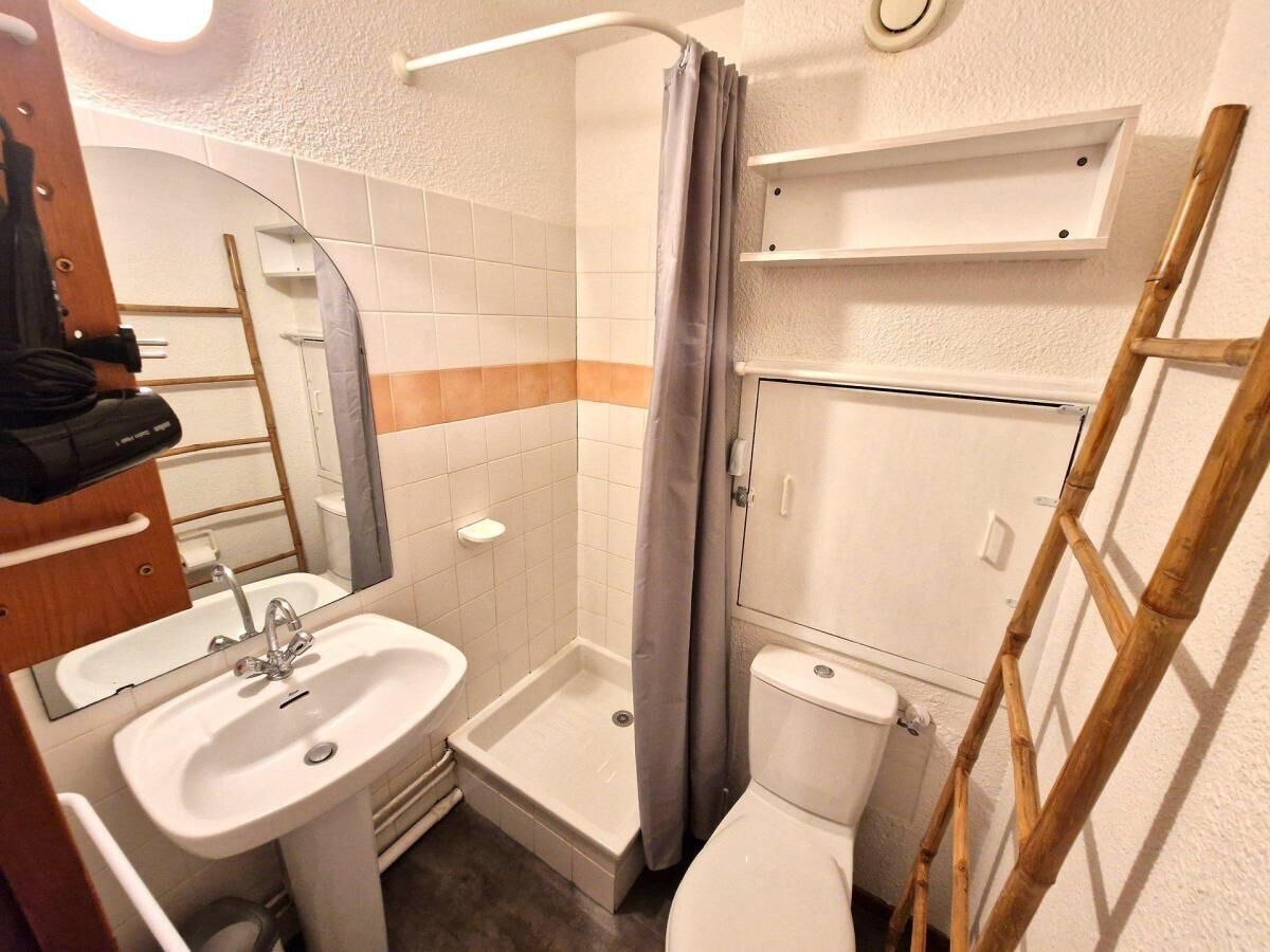 Een kleine badkamer met een wastafel, toilet en douche.