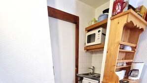 A compact kitchen with a wooden table and chairs, a microwave, and a small refrigerator.