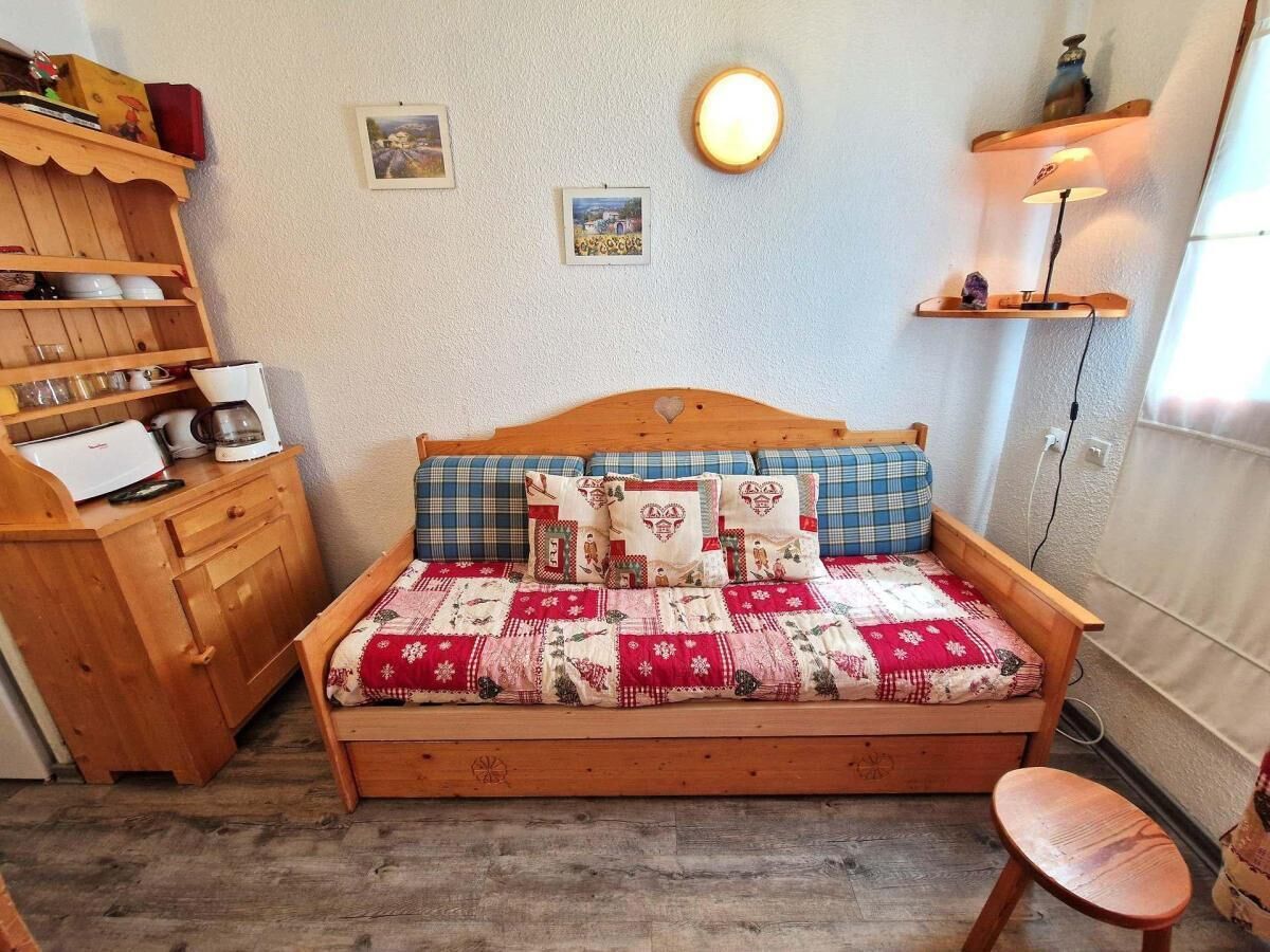 Ein gemütliches Zimmer mit einem hölzernen Bett, einer Holzkommode und einem kleinen Hocker.