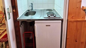 A compact kitchenette with a microwave, stove, sink, and a small refrigerator.