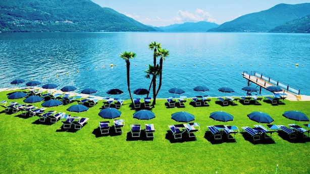 Um resort com área de piscina, espreguiçadeiras, guarda-sóis e palmeiras.
