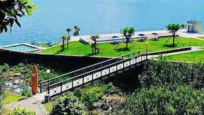Vista de uma propriedade à beira do lago com piscina, ponte e estacionamento.
