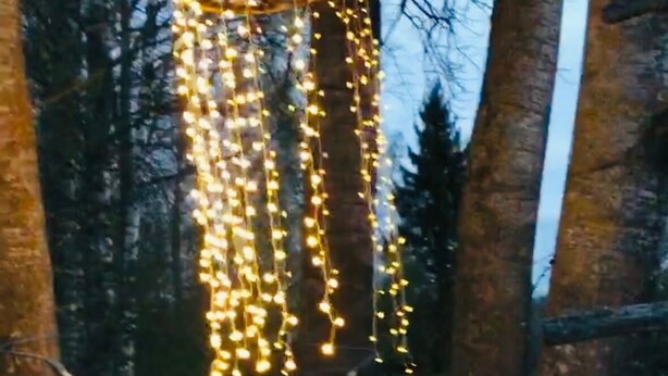 Un área de estar al aire libre con suelo a cuadros, una hamaca y luces colgantes.