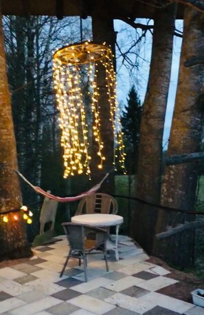 An outdoor seating area with a checkered floor, a hammock, and string lights hanging from a structure. - Cozy Cabin Retreat in Avesta (Avesta)