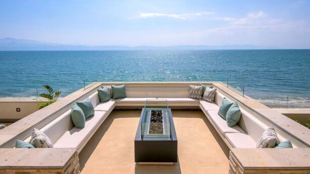 A sunlit outdoor seating area with a view of the sea, featuring a sofa and a coffee table. - New beachfront condo with pool and ocean views in welcoming Bucerías (Bucerías)