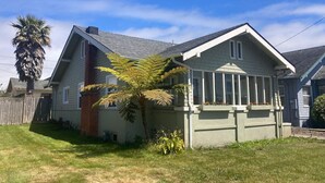 A single-story house with a sloped roof, a brick chimney, and a small front yard with a palm tree. - Henderson Hideout-Hot Tub and Pet Friendly! (Eureka)