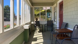 A covered porch with a table and chairs, large windows, and a door. - Henderson Hideout-Hot Tub and Pet Friendly! (Eureka)
