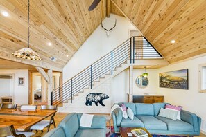 A spacious living area with a wooden ceiling, a staircase, a dining table, and a sofa. - Beautiful Ocean View Cabin and Hot Tub!! (Trinidad)