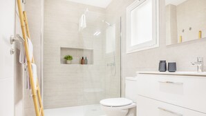 Un baño moderno con inodoro, ducha y tocador con espejo.