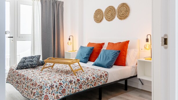 Une chambre à coucher moderne avec un lit, des tables de chevet et une fenêtre avec des rideaux.