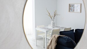 Un salon moderne avec un grand miroir rond qui reflète l’espace repas.