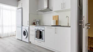 Une cuisine moderne avec des meubles blancs, un four encastré, un four à micro-ondes et un lave-linge.
