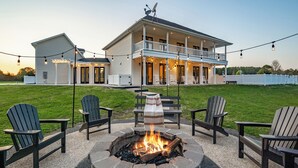 Ein zweistöckiges Haus mit Feuerstelle inmitten Adirondack-Stühlen.