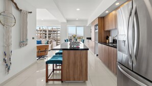 Uma cozinha moderna com uma ilha central, eletrodomésticos de aço inoxidável e vista para o exterior.