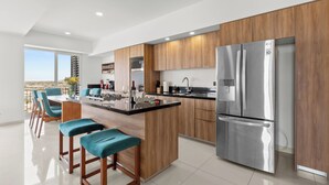 Cozinha moderna com ilha central, eletrodomésticos de aço inoxidável e armários de madeira.