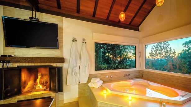 Un baño moderno con una bañera grande, una chimenea y un televisor montado en la pared.