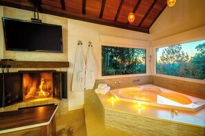 Une salle de bain moderne avec une grande baignoire, une cheminée et un téléviseur fixé au mur.
