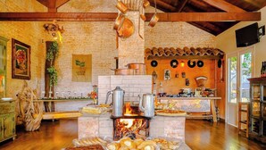 Una cocina rústica con estufa de leña, diferentes utensilios de cocina y diversos alimentos exhibidos sobre la encimera.