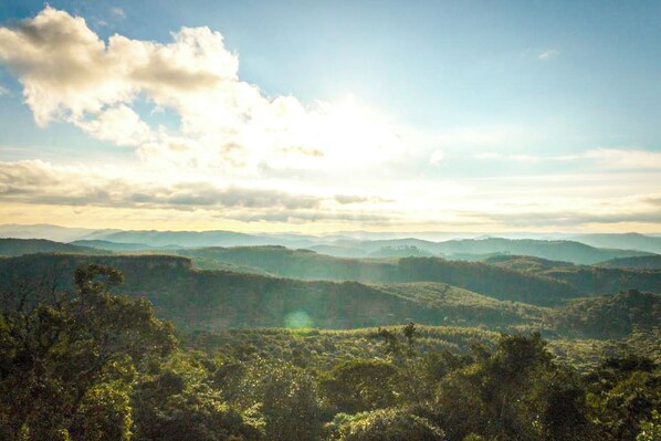 A panoramic view of a mountainous landscape with dense forest coverage and distant hills. - Inn Pedras e Sonhos (Camanducaia)