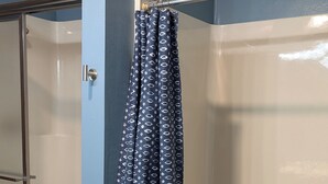 Une salle de bain avec un rideau de douche, une baignoire et une cabine de douche en verre.