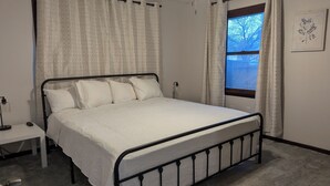 Une chambre à coucher avec un lit, une table de chevet, une fenêtre donnant sur un beau paysage et une plante fixée au mur.
