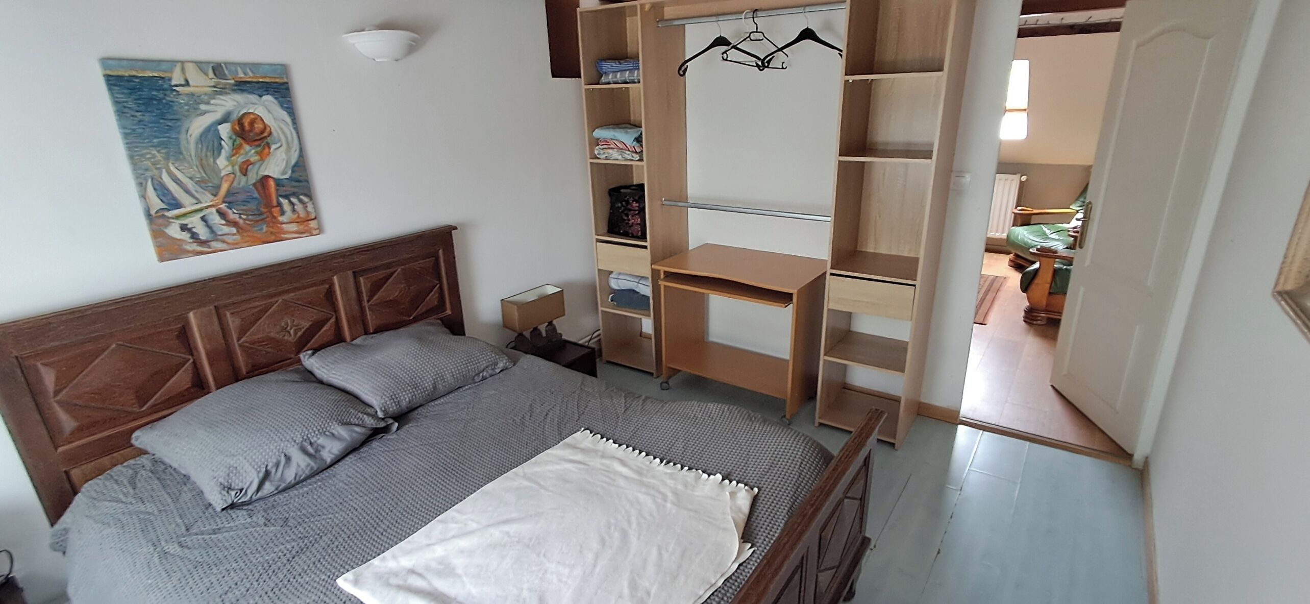 Ein Schlafzimmer mit einem Bett, einem Nachttisch, einem Holzschrank und einem Gemälde an der Wand.