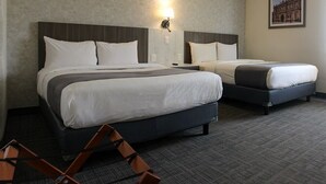 Et hotelværelse med to senge, et natbord, en lampe og et billede i ramme på væggen.
