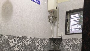 Un baño con inodoro, ducha y dos cubetas.
