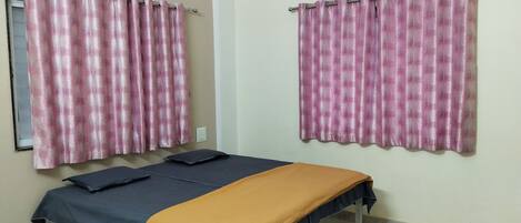 A room with a bed, two pillows, a window, and an air conditioner.