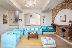 A spacious living room with a fireplace, a staircase, and a cozy seating area. - Villa Anser - Four Bedroom Villa, Sleeps 10 (Limni)