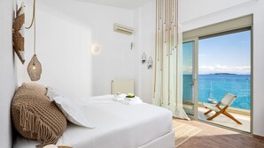 Un dormitorio con cama, vista al mar y una silla junto a la ventana.