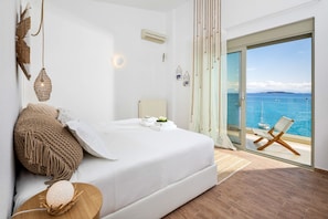 A bedroom with a bed, a view of the sea, and a chair by the window. - Villa Anser - Four Bedroom Villa, Sleeps 10 (Limni)