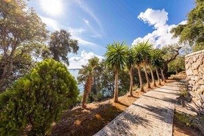 A stone pathway leading to a body of water, surrounded by trees and vegetation. - Villa Anser - Four Bedroom Villa, Sleeps 10 (Limni)
