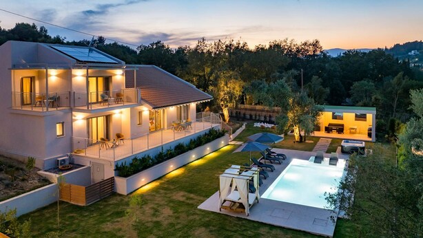 Ein modernes, zweistöckiges Haus mit Swimmingpool, Sitzgelegenheiten im Freien und einer gut beleuchteten Terrasse.