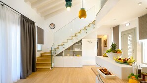 Ein modernes Interieur mit Treppe, Holzboden und einer Küchenzeile mit Obst und Snacks.