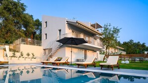 A modern two-story house with a swimming pool, outdoor seating, and a staircase leading to a balcony.