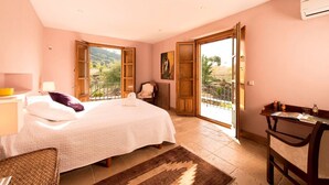 Un dormitorio con cama, una silla, un escritorio y vistas al exterior.