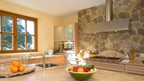 Una cocina moderna con salpicadero de piedra, un ventanal y un frutero en la encimera.
