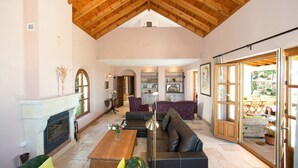 Un salón espacioso con chimenea, un sofá grande, una mesa de centro y una zona de comedor con sillas.