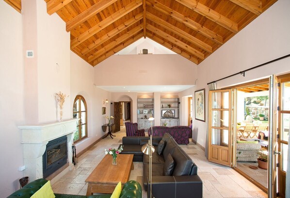Un salón espacioso con chimenea, un sofá grande, una mesa de centro y una zona de comedor con sillas.