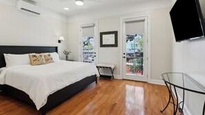 A bedroom with a bed, a ceiling fan, a TV, and a balcony door.