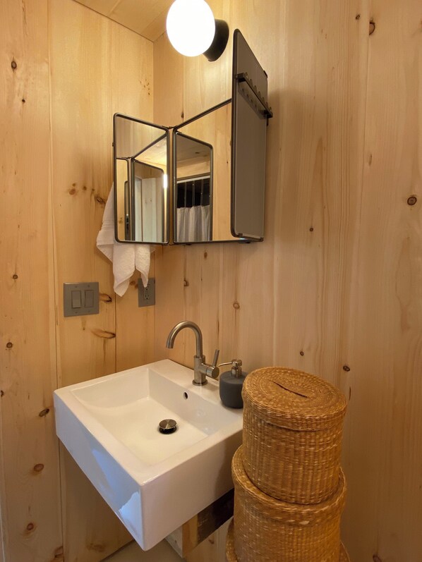 A bathroom with a white sink, a mirror, and a light fixture.