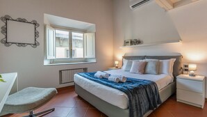 Makuuhuone, jossa on sänky, yöpöydät, tuoli, ikkuna ja ilmastointilaite.