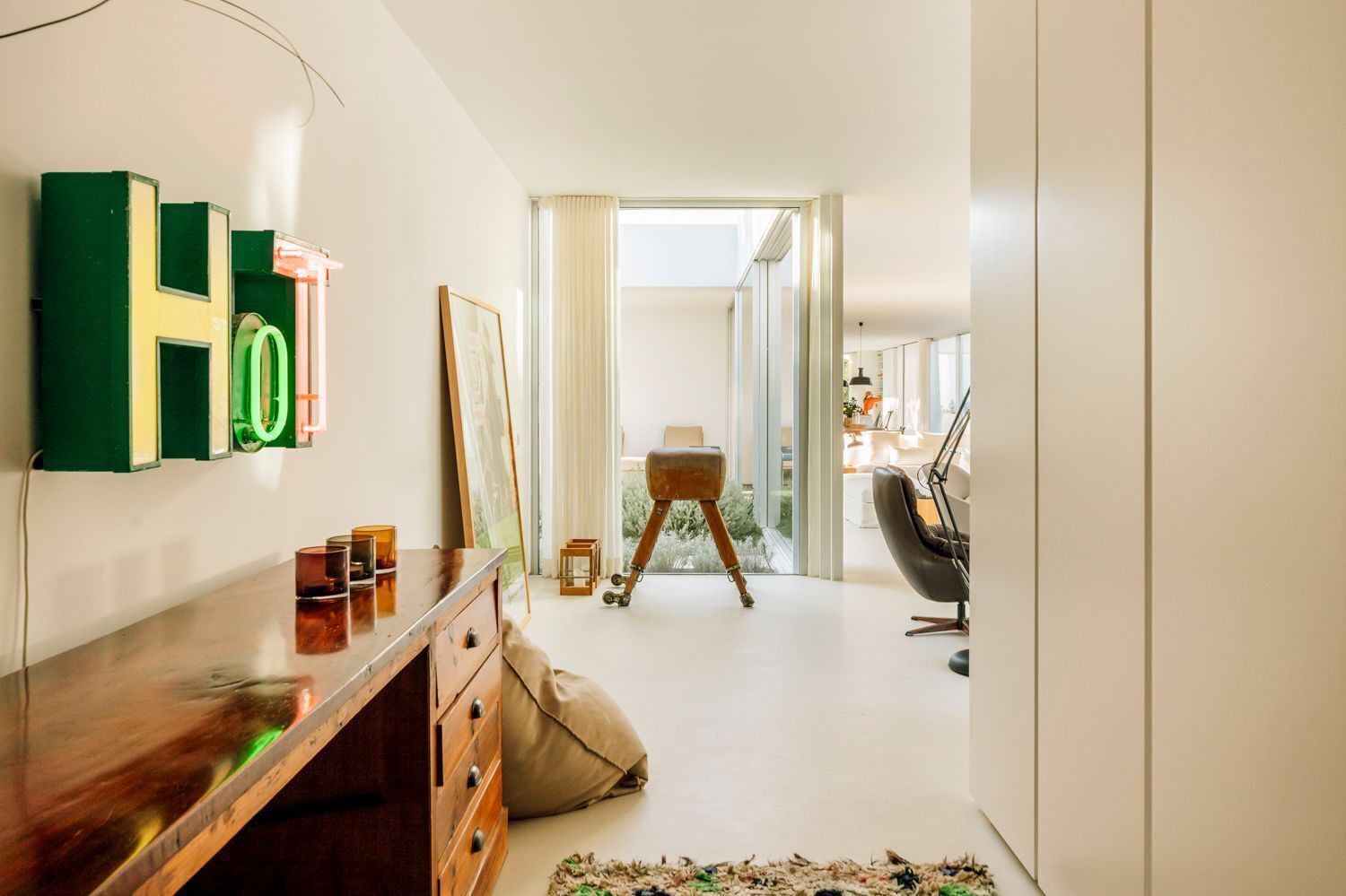 Une pièce moderne avec un bureau en bois, une enseigne verte et jaune, un tableau encadré, un petit tabouret et une chaise.