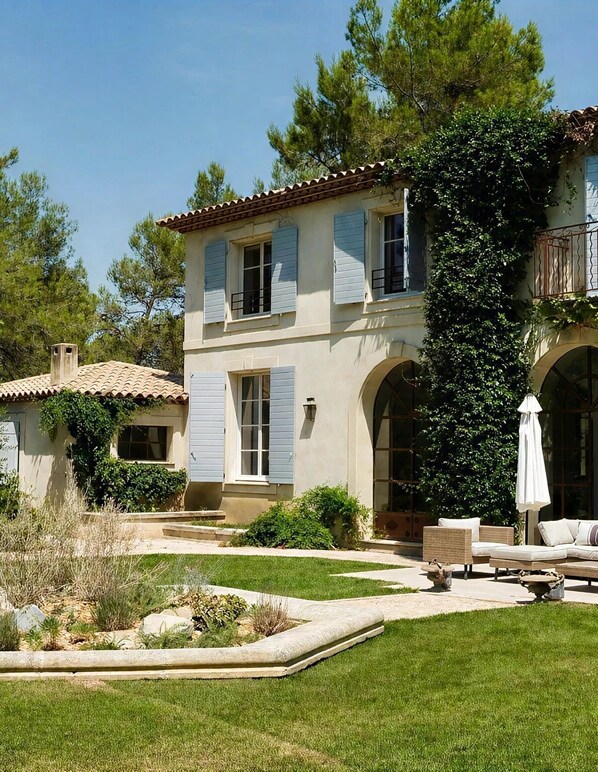 A two-story house with a garden patio, outdoor furniture, and a large window overlooking the garden.