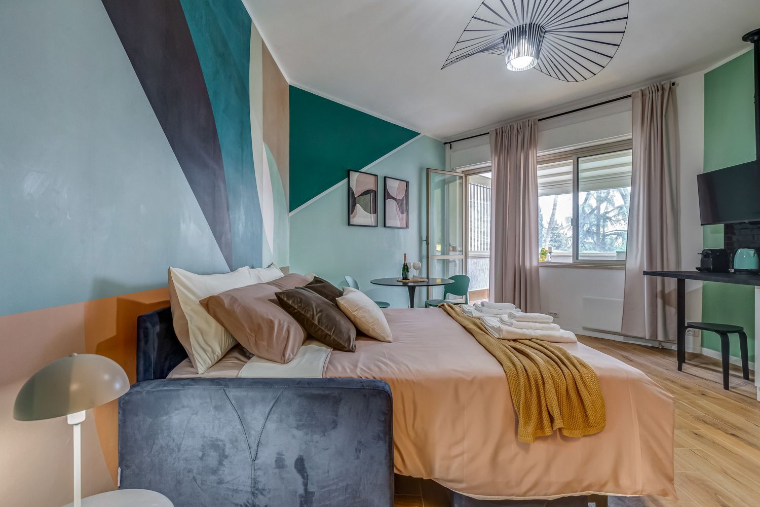 Ein modernes Hotelzimmer mit einem Bett, einem Schreibtisch, einem Sessel und einem Fernseher.